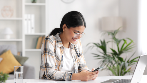 Happy young woman texting on phone