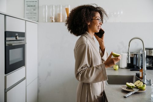 Smiling woman talking on cell phone eating an apple