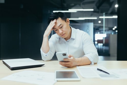 Stressed man holding smart phone