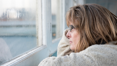 Woman looking out rainy window