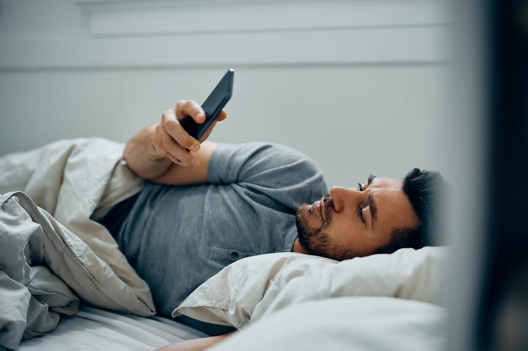 Man using phone in bed